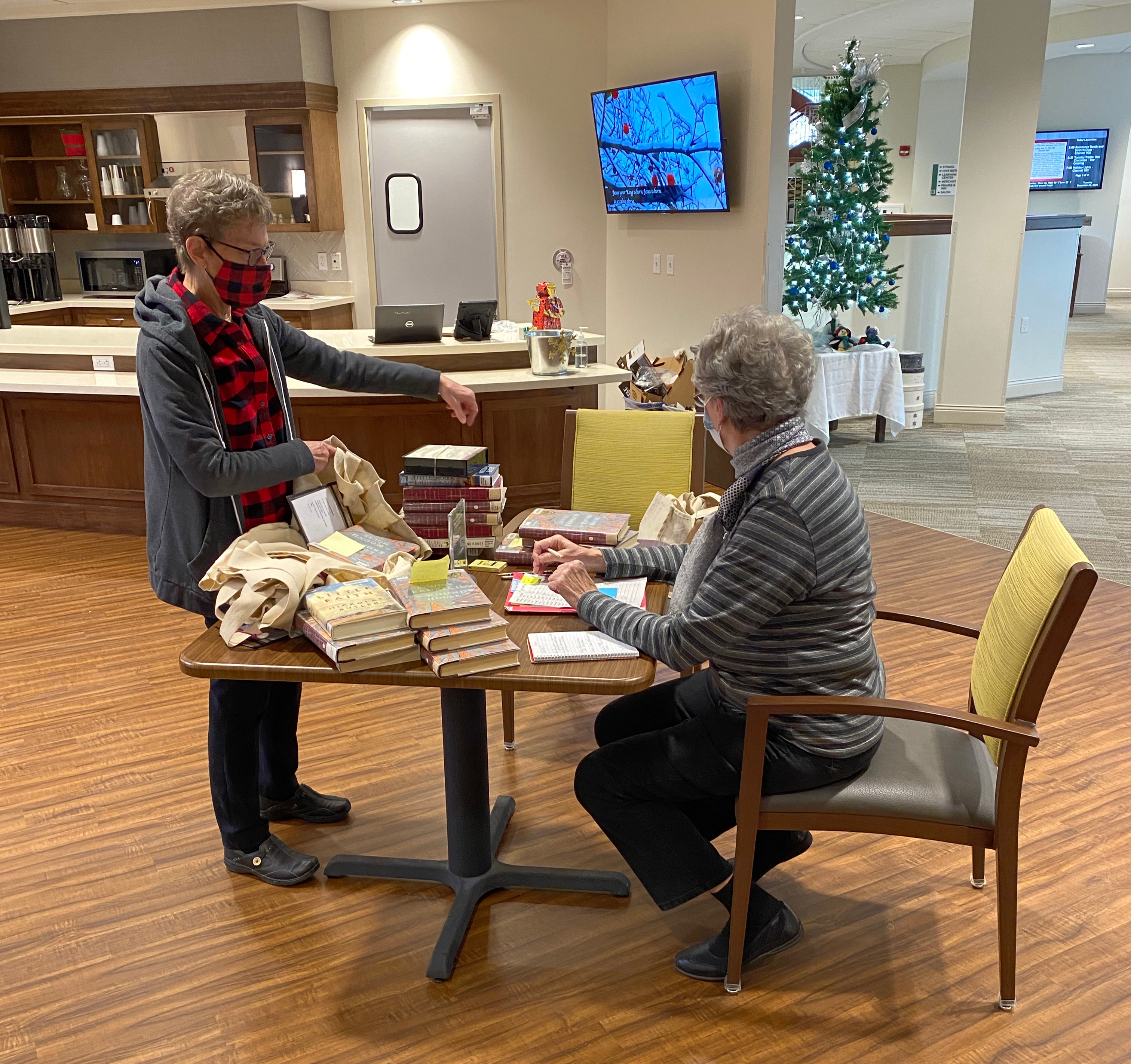 Resident volunteers at Oak Village Prairie Ridge process books for their facility mini-library