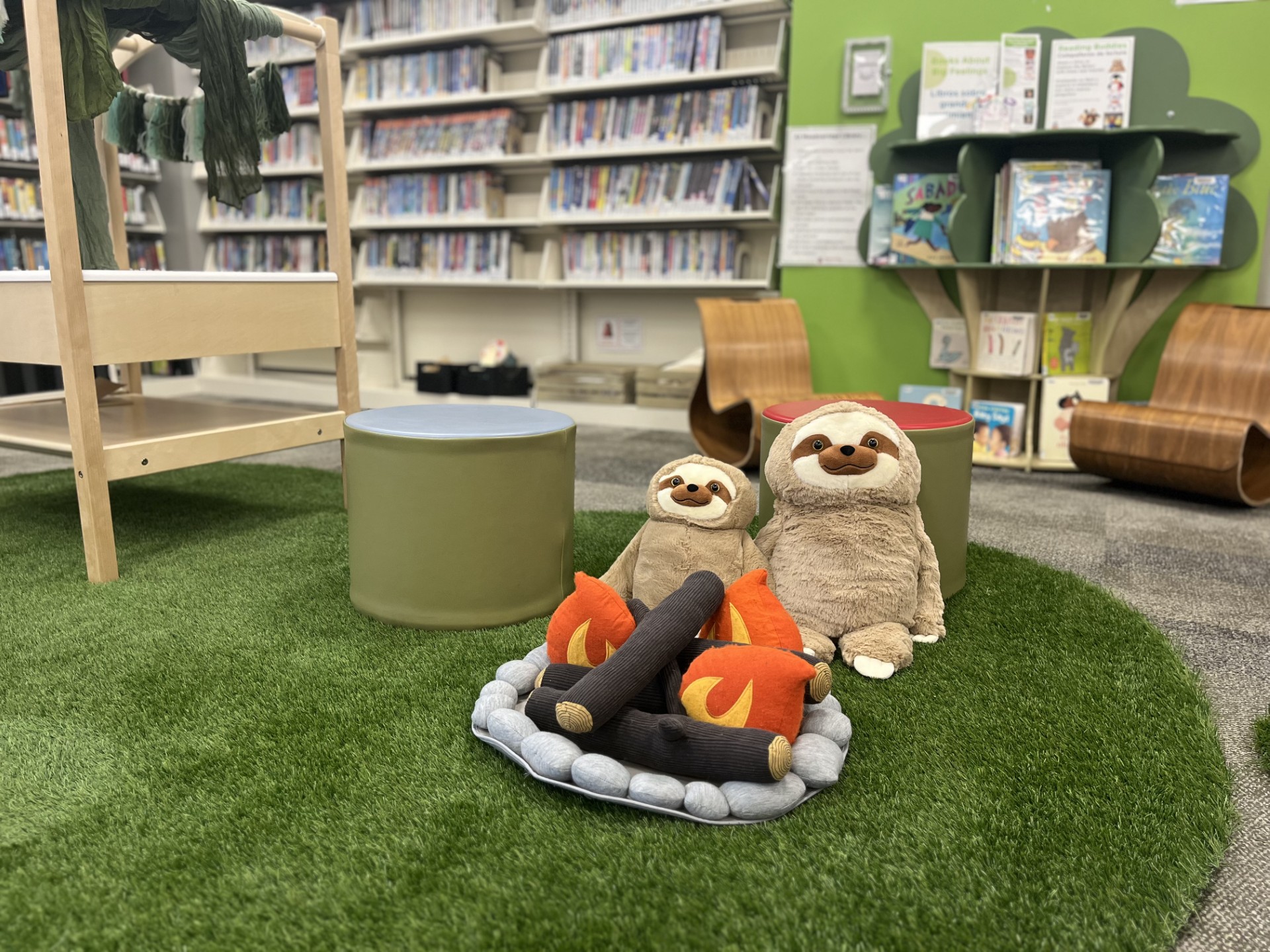 Meadowridge Library Play Space features Treehouse vibe with reading buddies, grass, and fake campfire