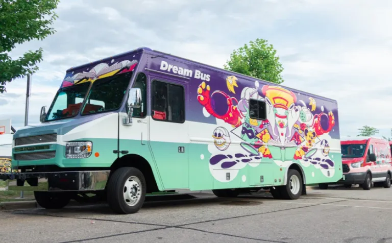 The Dream Bus, a blue and green bookmobile, in a parking lot